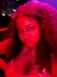 a woman with long curly hair in a red light